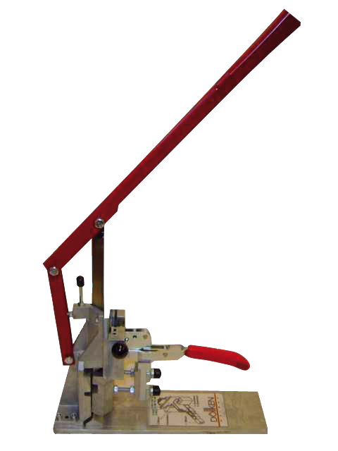 Une presse manuelle de table avec un long levier rouge et une petite poignée rouge montée sur une base métallique, utilisée pour percer ou presser de petites pièces. La presse possède un bras articulé, des éléments réglables et une plaque de base rectangulaire avec des instructions imprimées.