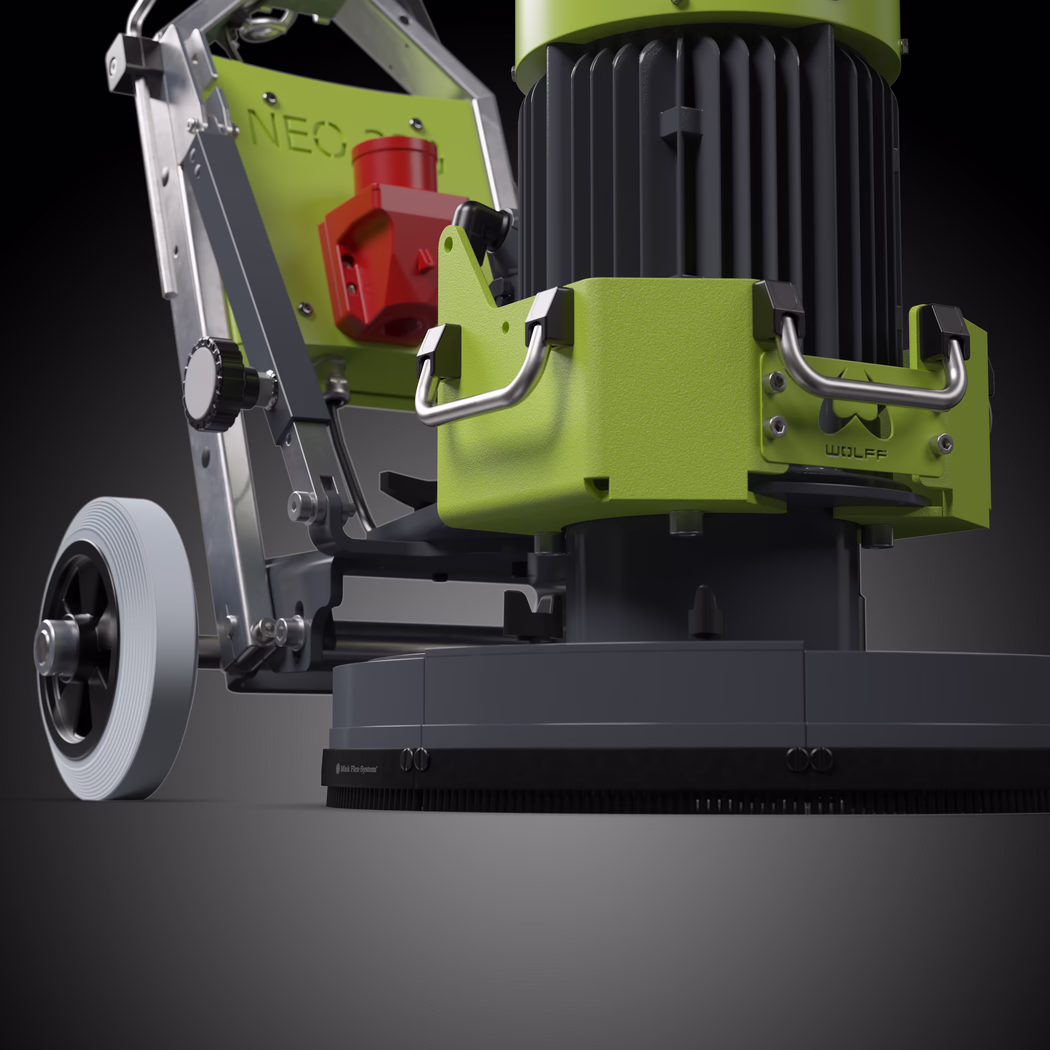 Close-up view of a professional floor machine captured in high-contrast black-and-white. The composition focuses on the lower motor and brush housing from a low angle, emphasizing the ribbed industrial electric motor, the textured metal protective casing with two robust stainless-steel handles, and the round polishing base with a dense brush skirt. To the left, a large solid wheel with concentric tread is visible, mounted to a sturdy aluminum frame with adjustment knobs, bolts and hinge elements; the frame plate shows a faint embossed "NEO" while a small nameplate on the housing reads "WOLFF". Directional lighting from above and slightly front-left creates crisp highlights on machined metal surfaces and deep shadows that accentuate form and material, giving the scene a technical, tactile quality. The image conveys scale, weight and mechanical detail—smooth cast parts, brushed metal handles, a knurled adjustment knob, exposed fasteners and rubberized trim—suitable for product catalog imagery or technical documentation.